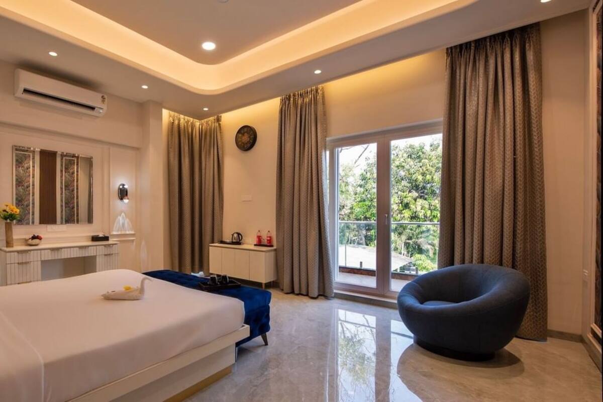 Una habitación de hotel moderna con cama, una silla, un escritorio y una ventana con cortinas.
