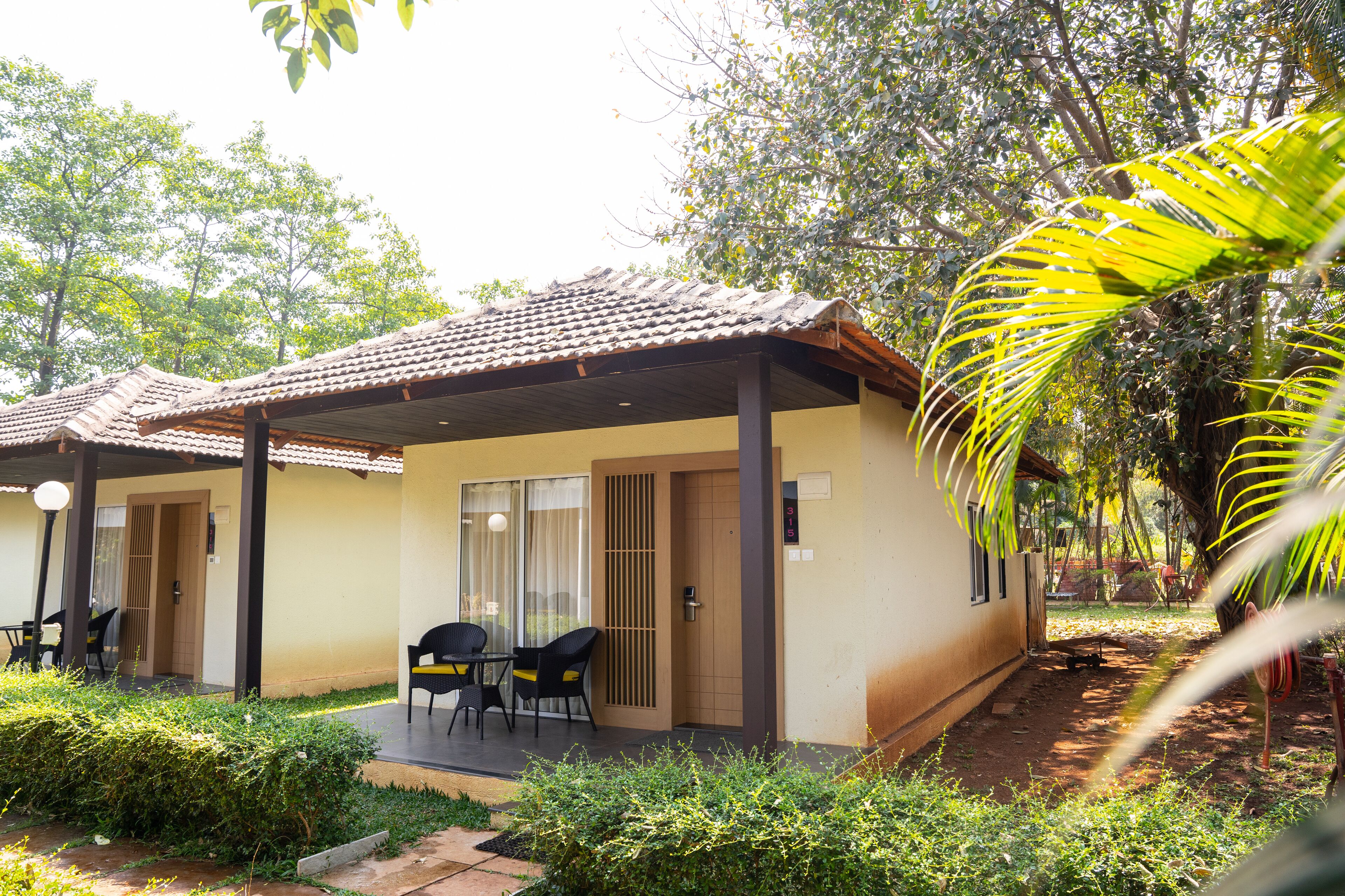 A small, single-story building with a tiled roof and a covered patio area with two chairs and a table.