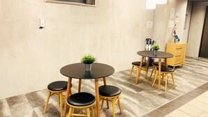 A hotel room with a round table and four chairs, a small potted plant, and a wooden cabinet. - At RLiS House Tsutenkaku (Osaka)