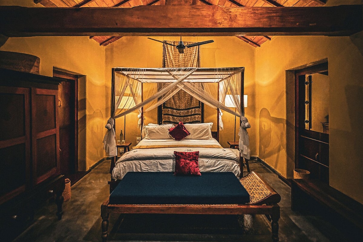 A spacious bedroom with a large bed, wooden ceiling beams, and a canopy bed.