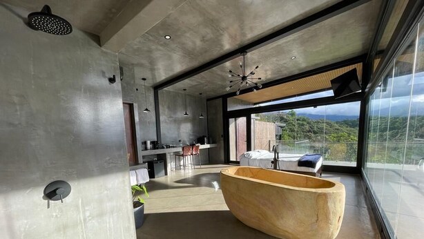 Een modern interieur met een groot houten bad, een keukenhoek en uitzicht op de omgeving.