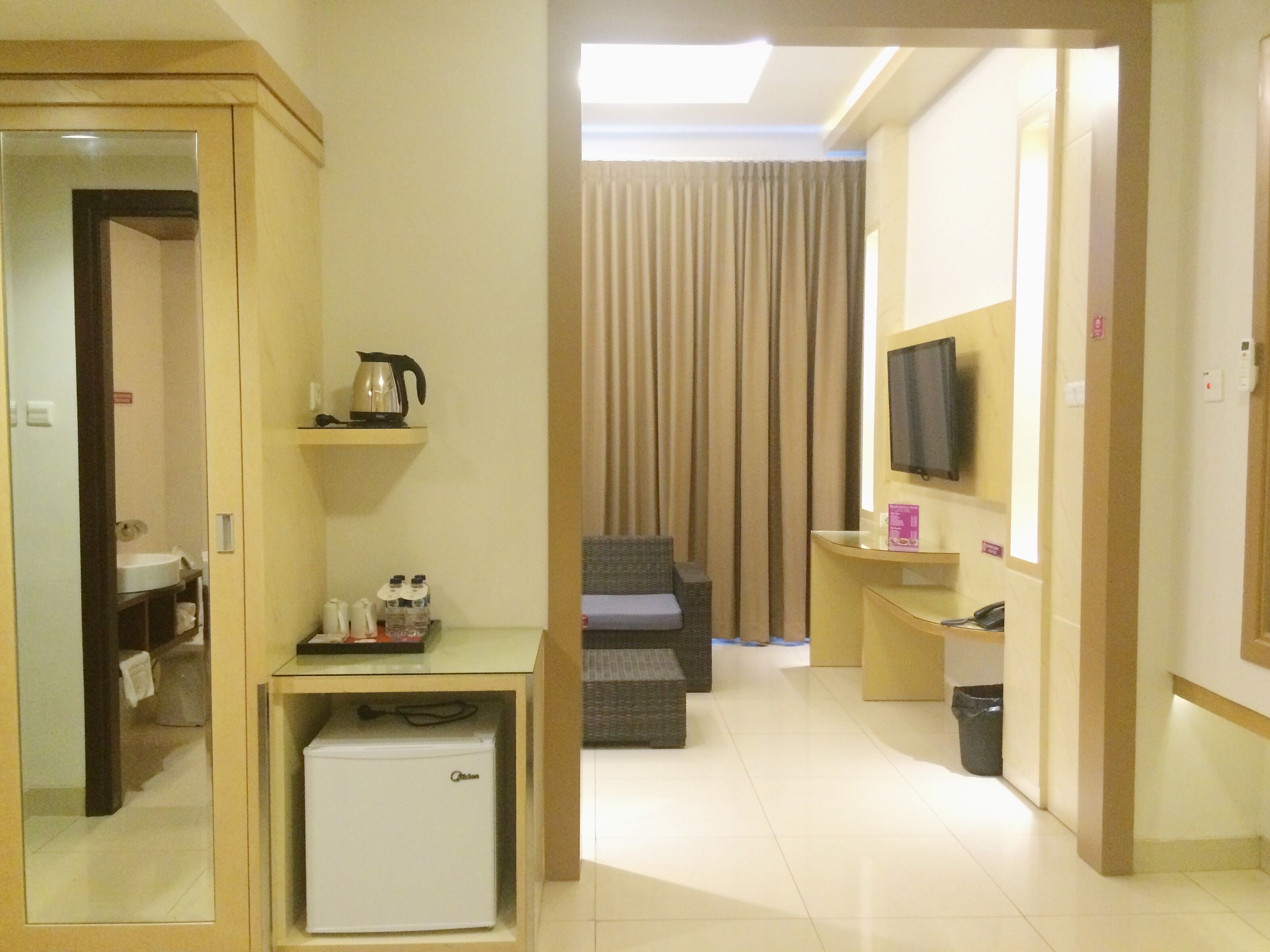 Une chambre d’hôtel équipée d’une kitchenette, d’un téléviseur à écran plat, d’un canapé et d’un rideau.