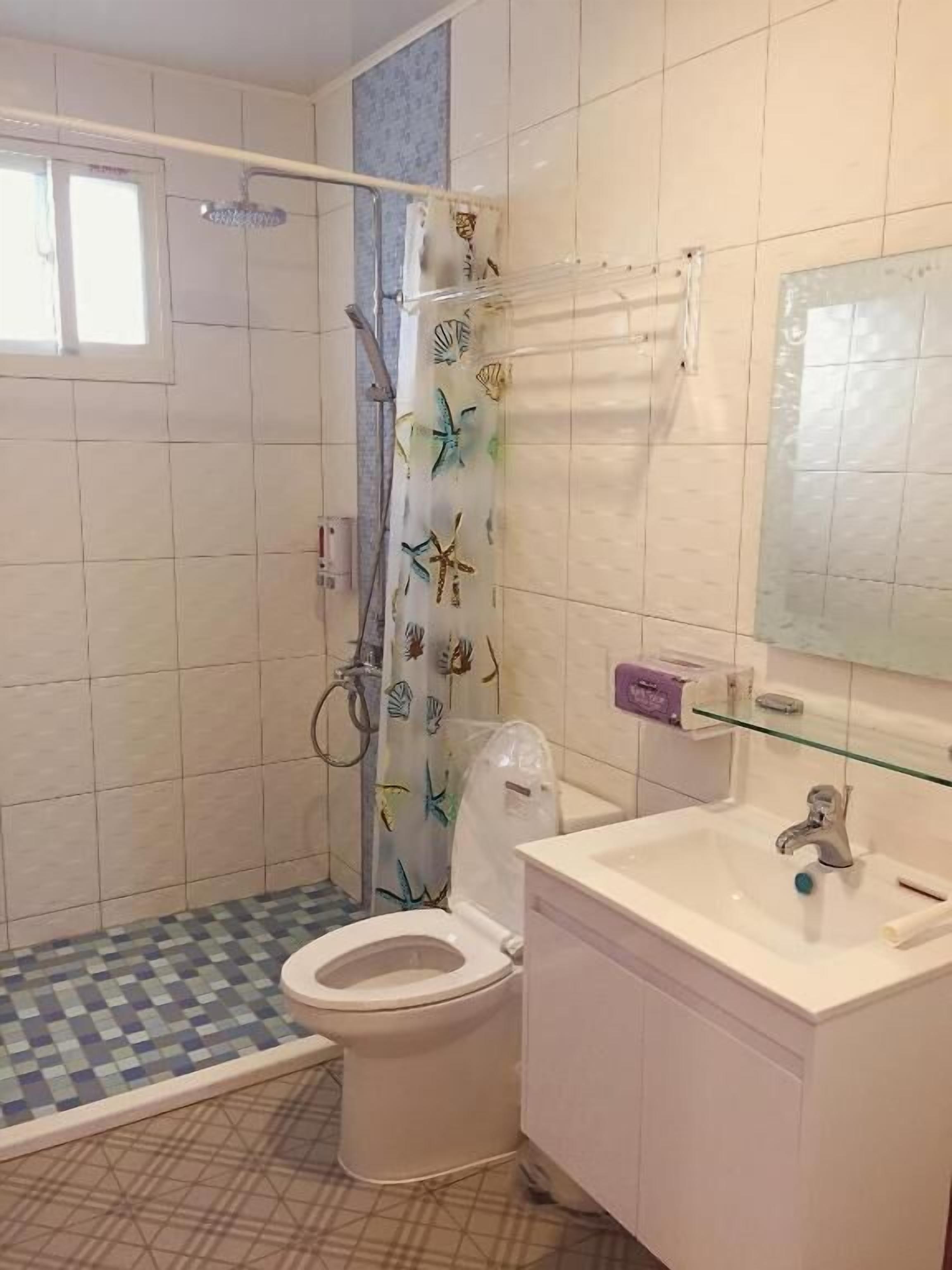 A bathroom with a shower, toilet, and sink.