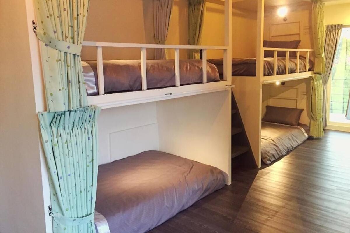 A bunk bed room with curtains, a staircase, and a window.