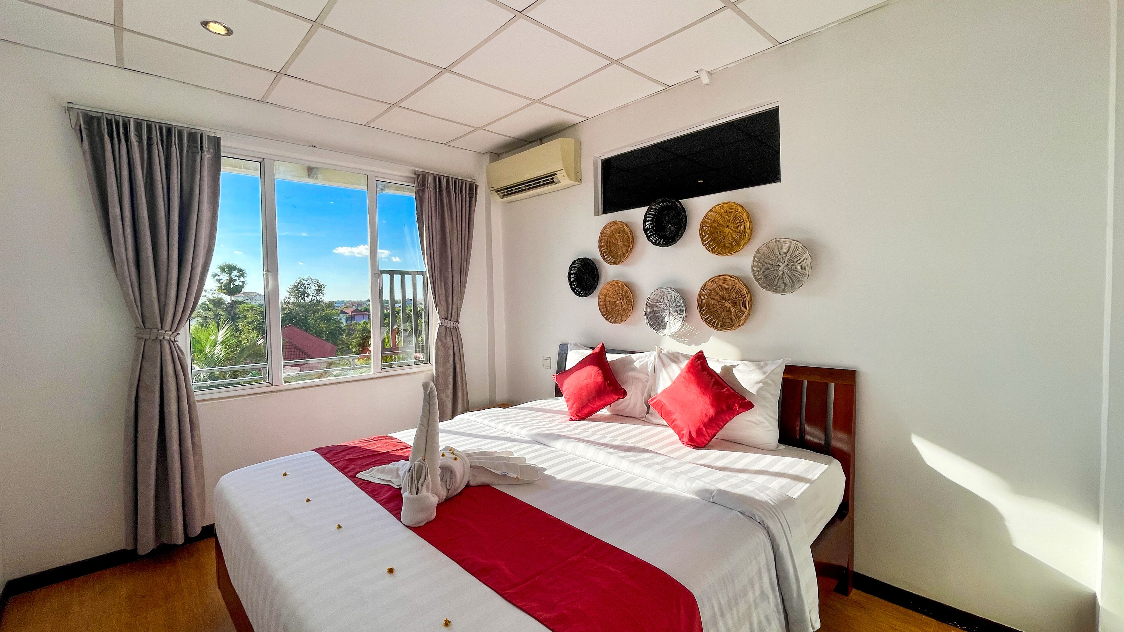 Une chambre d’hôtel avec un grand lit, une vue sur la verdure et un climatiseur fixé au mur.