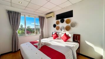 Une chambre d’hôtel avec un grand lit, une vue sur la verdure et un climatiseur fixé au mur.