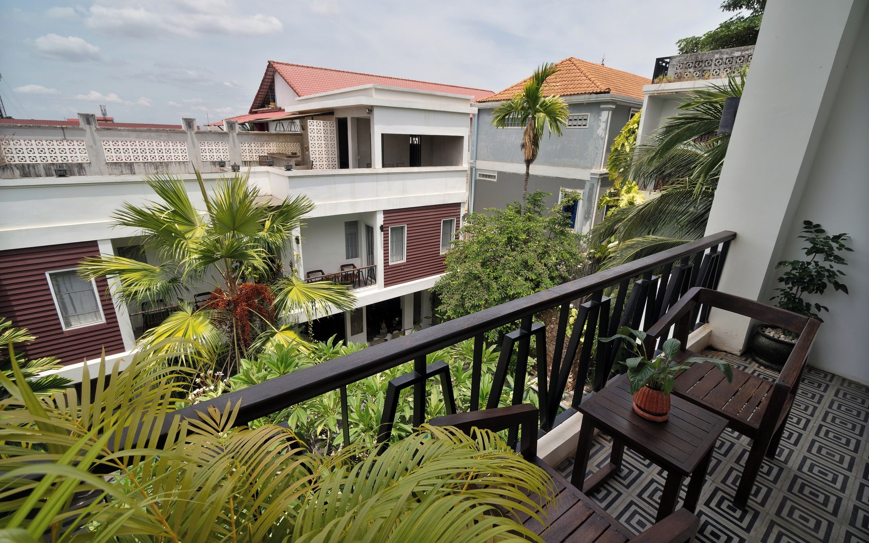A residential building with multiple balconies, some with plants and outdoor furniture.