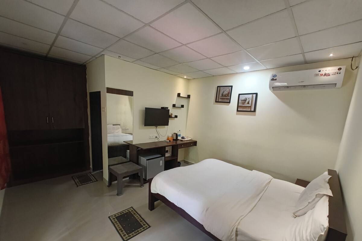 A hotel room with a bed, desk, chair, and a television.