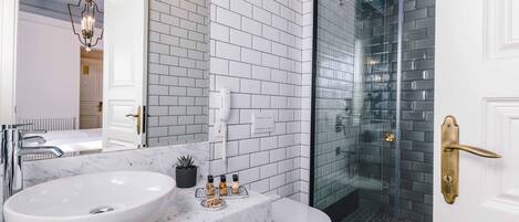 A bathroom with a white sink, marble countertop, and a glass shower enclosure.