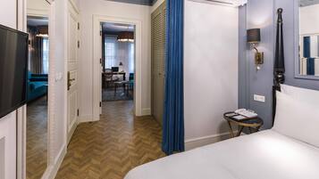 A hotel room with a bed, a desk, a chair, a television, and a bathroom with a mirror.