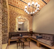 Una habitación acogedora con pared de ladrillo, un espejo grande y una lámpara moderna. Hay dos sofás y una mesita con adornos.