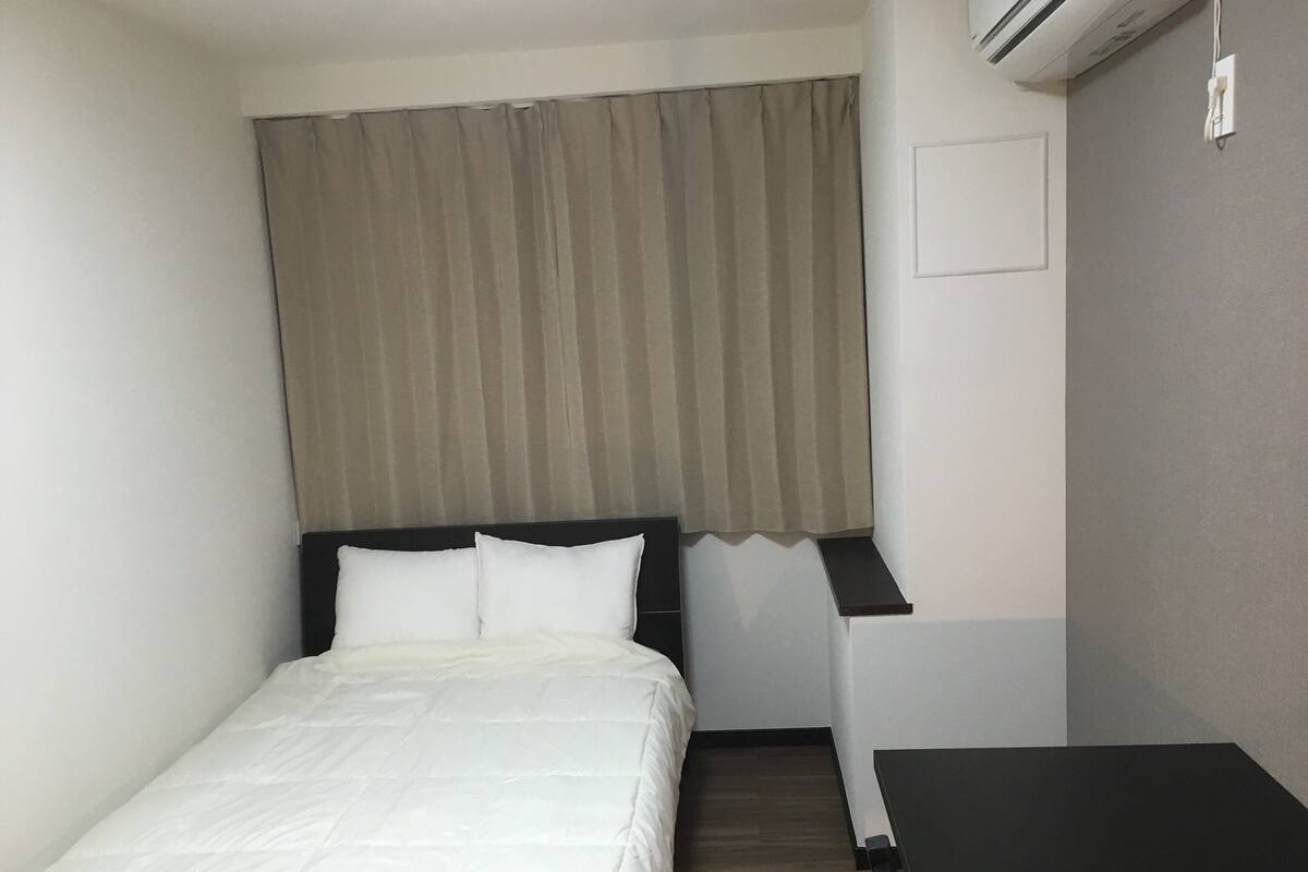 Ein Hotelzimmer mit einem Bett, einem Schreibtisch und einer Klimaanlage.