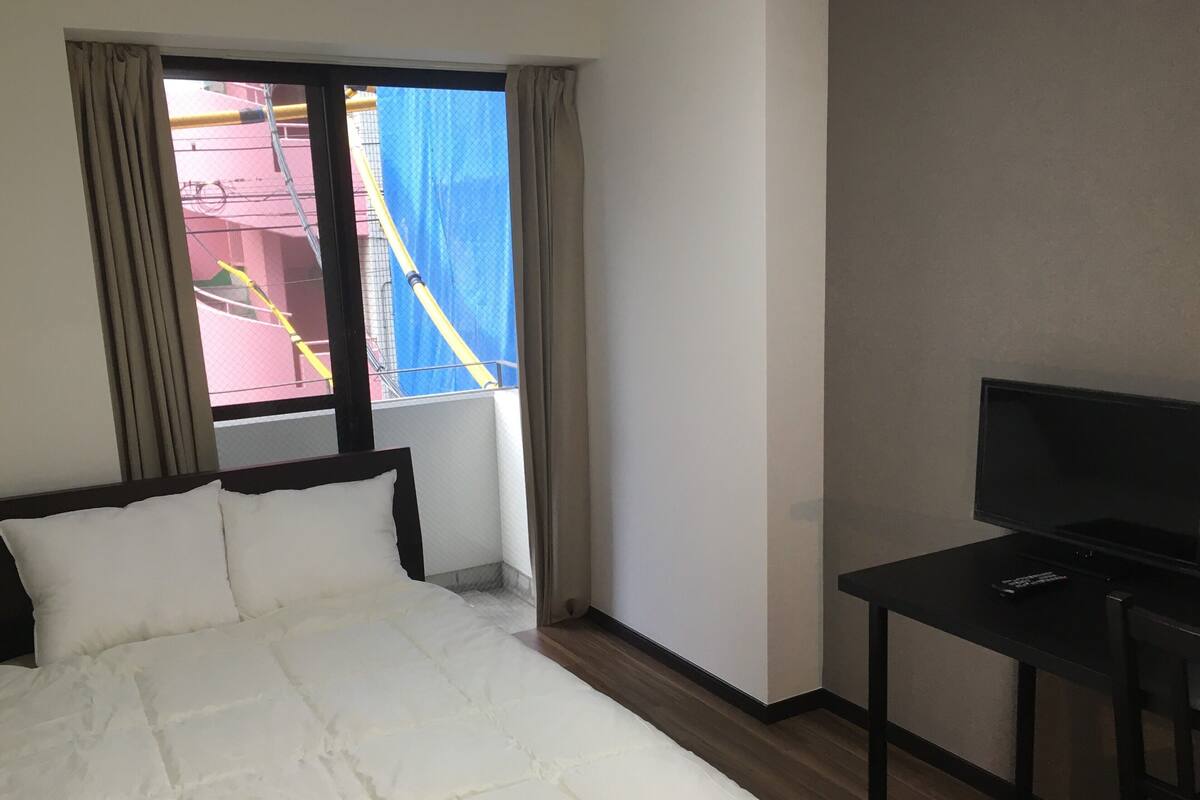 Ein Hotelzimmer mit Bett, Fernseher und einem Fenster mit Vorhängen.