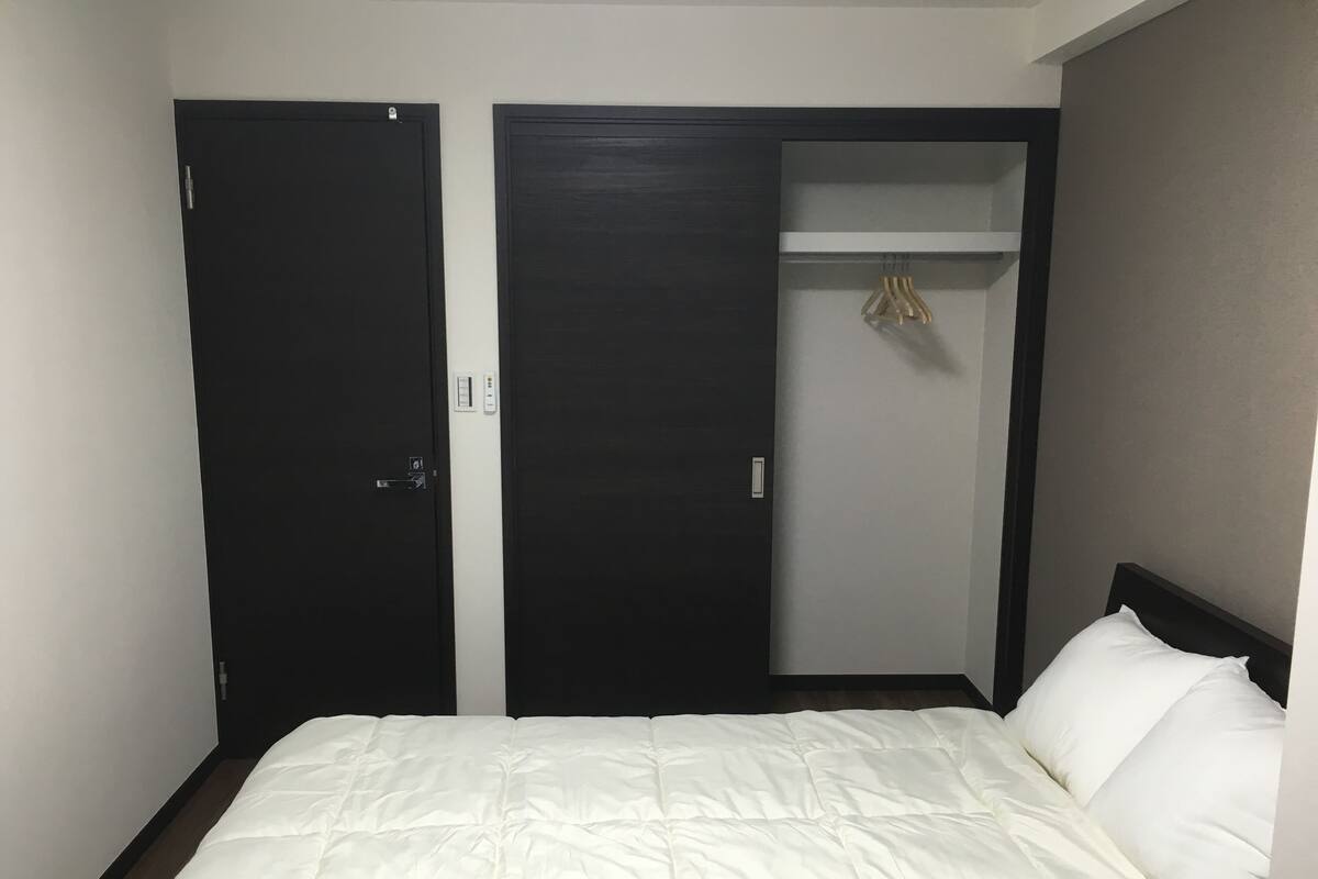 Ein Schlafzimmer mit einem Bett, zwei Türen und einem Schrank mit Kleiderstange.
