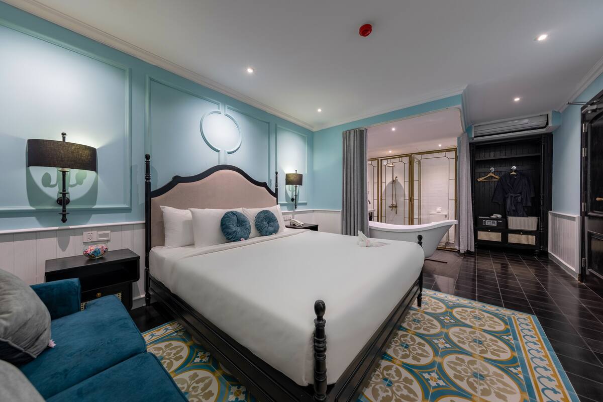 A spacious bedroom with a large bed, bedside tables, a vanity, and a bathroom with a bathtub and shower.