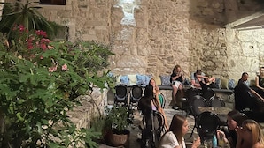 An outdoor seating area with stone walls and wooden shutters, surrounded by potted plants and flowers. - Luxury Rooms MA de Dominis - Adults Only (Split)