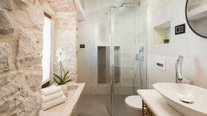 A modern bathroom with a stone wall, a glass shower enclosure, a white sink, and a mirror. - Luxury Rooms MA de Dominis - Adults Only (Split)