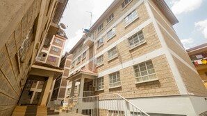 Un immeuble résidentiel à plusieurs étages, doté de balcons, de paraboles de télévision par satellite et d’une entrée sécurisée par un portail.