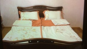 A bed with a wooden frame, two pillows, and a floral bedspread. - Luxury apartment in Yerevan (Arabkir)