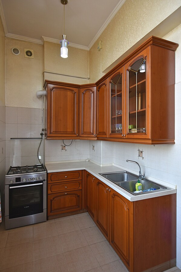 A kitchen with wooden cabinets, a stainless steel stove, and a sink.