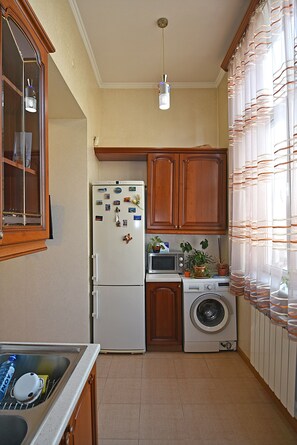 A compact kitchen with a refrigerator, microwave, and washing machine.