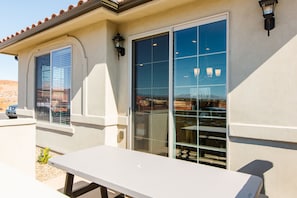 Relax on the outdoor patio with a table and bench, adjacent to a building with large glass doors.