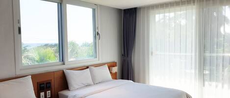 A hotel room with two beds, a large window with a view, and a curtain.