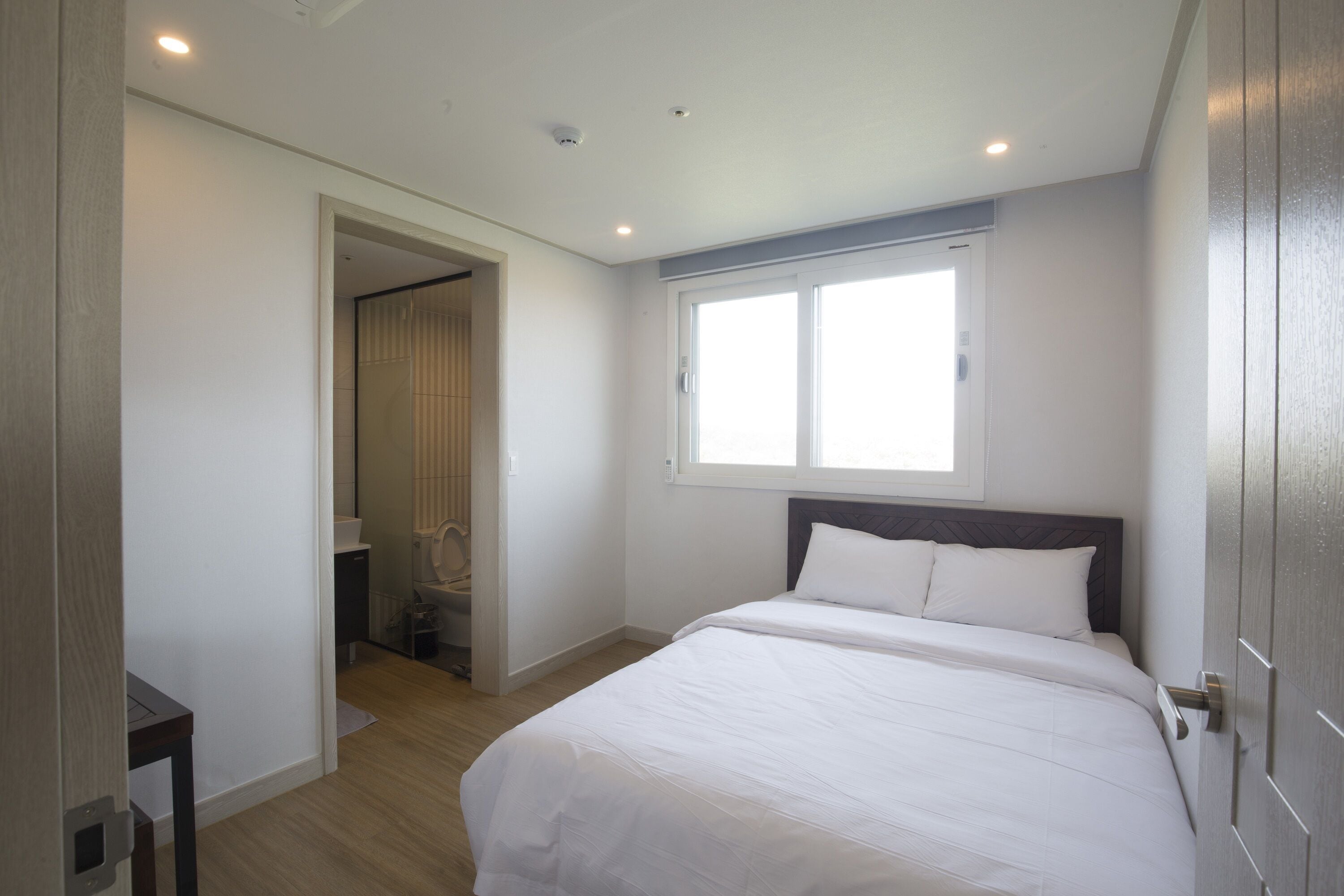 Une chambre à coucher avec un grand lit, une fenêtre et une porte donnant sur une autre pièce.