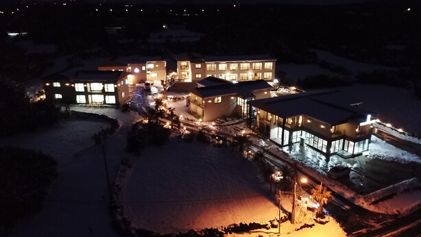 A snow-covered residential area with multiple illuminated buildings, suggesting a well-lit complex.