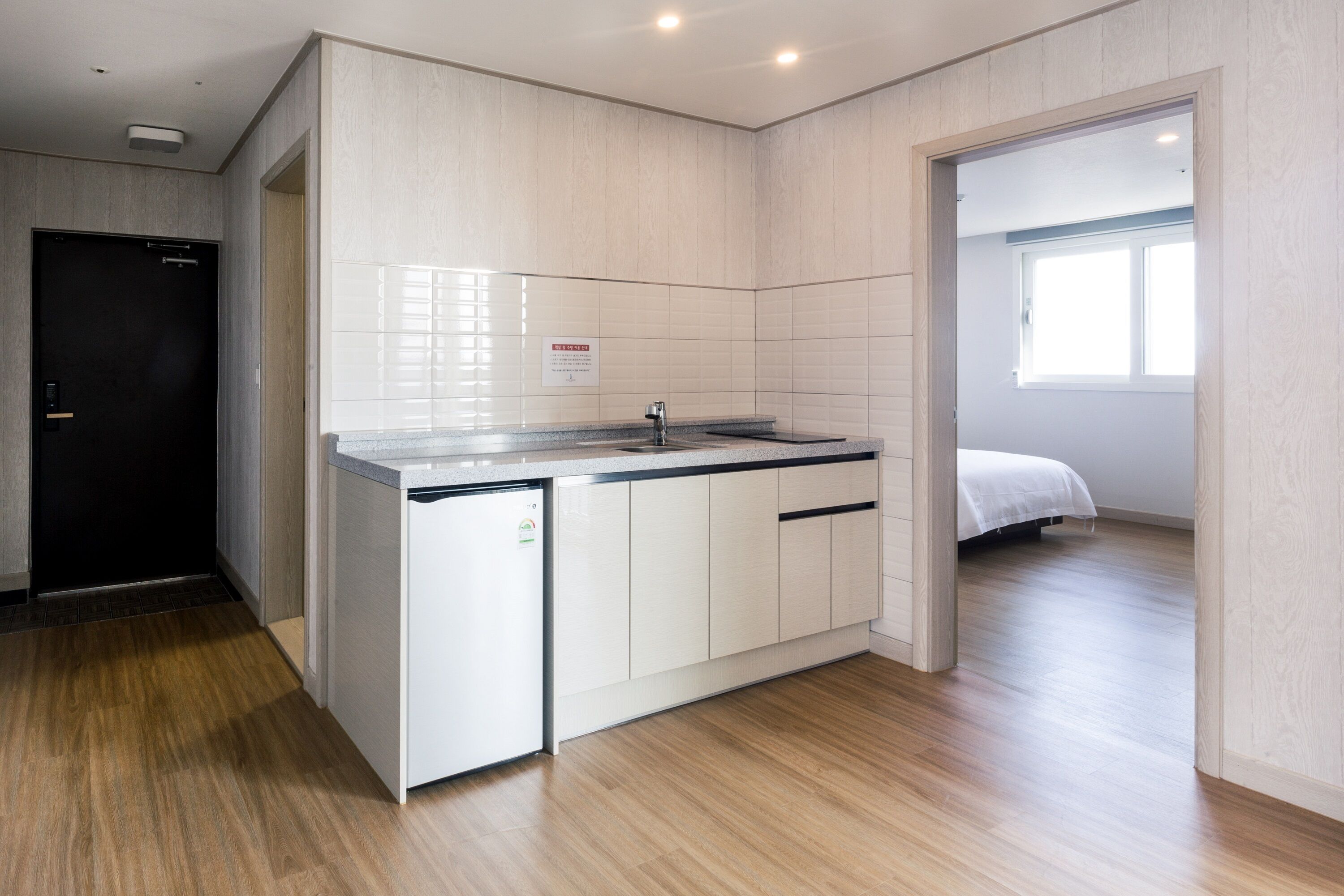A compact kitchen with white cabinets, a built-in sink, and a small refrigerator.