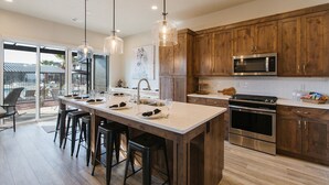 A modern kitchen with wooden cabinets, stainless steel appliances, and a central island with bar stools.