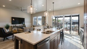 A modern kitchen with a central island, pendant lights, and a view to an outdoor patio.