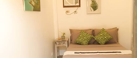 Un dormitorio con cama, mesita de noche y aire acondicionado de pared.