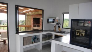 Cozinha compacta com micro-ondas embutido, geladeira com adesivo promocional e vista para um pátio através de uma janela grande.