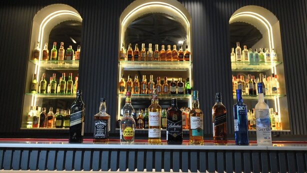 Eine Bar mit Regalen voller Spirituosenflaschen und einer Auswahl an Getränken hinter der Theke.