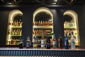 Un bar con estantes llenos de botellas de licores y una variedad de bebidas espirituosas en la barra.