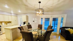 Een moderne keuken met een centraal eiland, een eettafel met stoelen en een hanglamp.
