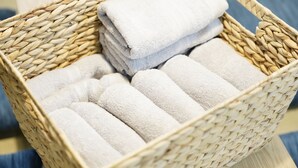 Una cesta de mimbre con toallas blancas dobladas con cuidado.