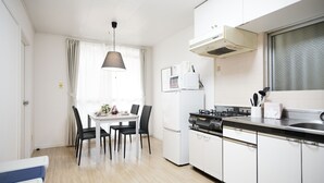 Una cocina moderna con armarios blancos, encimera negra y un comedor con mesa y sillas.
