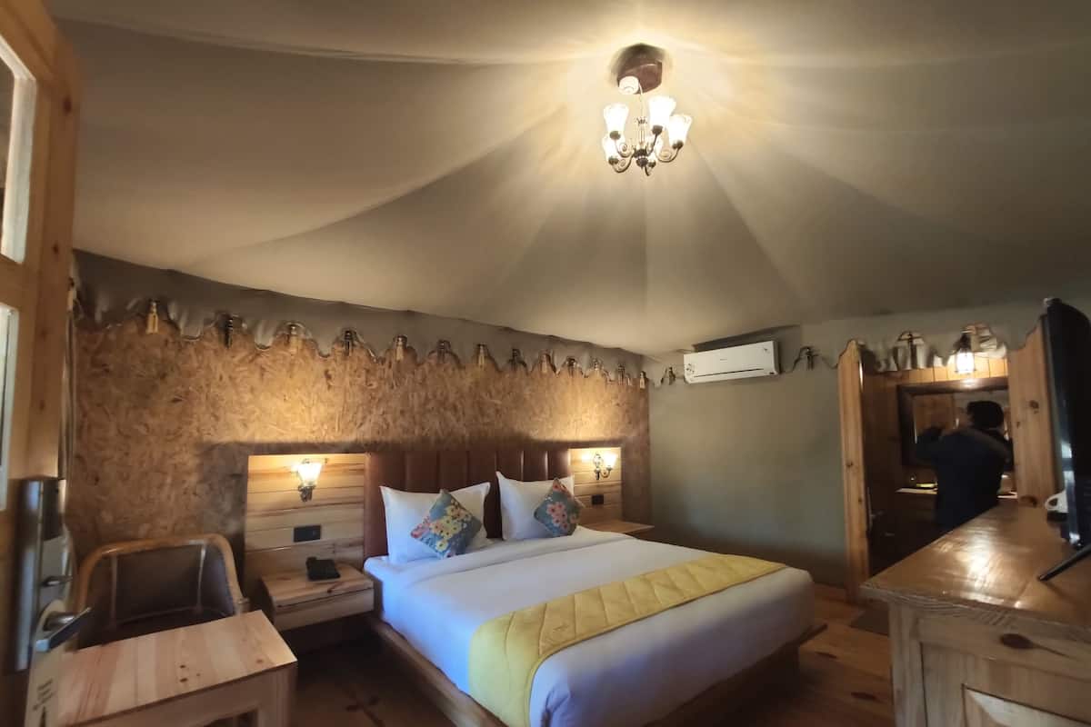A cozy bedroom with a wooden headboard, a bed with a yellow blanket, bedside tables with lamps, and a wooden dresser.