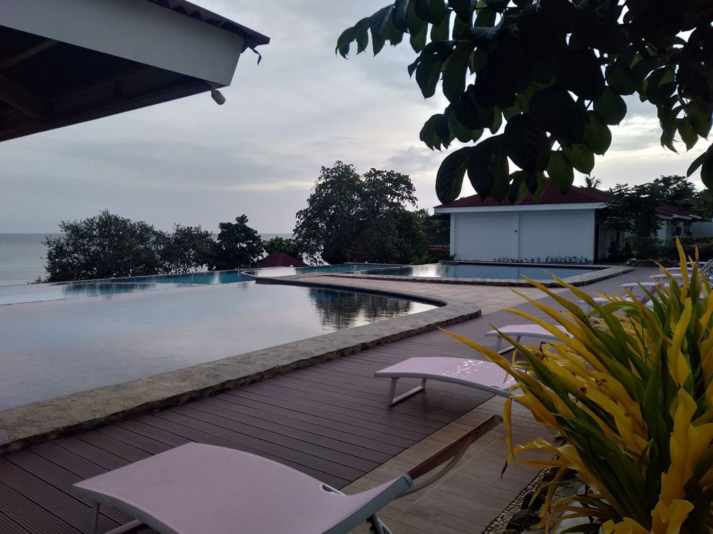Ein Swimmingpool mit Holzterrasse, Liegestühlen und Meerblick.