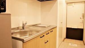 A small kitchenette with two stainless steel sinks, wooden cabinets, and a black microwave. - Mango Resort Okinawa Naha (Naha)
