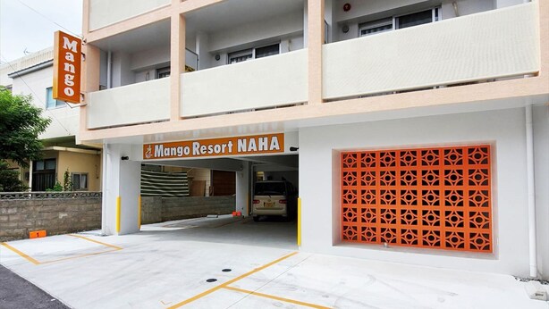 A building with a sign reading "Mango Resort NAHA" and a parking area with marked spaces. - Mango Resort Okinawa Naha (Naha)