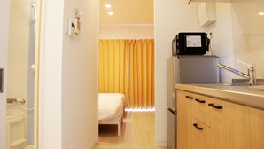 A compact hotel room with a bed, a kitchenette, and a bathroom. - Mango Resort Okinawa Naha (Naha)
