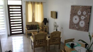 Un comedor con mobiliario de madera, una mesa lista para dos personas y un televisor montado en la pared.