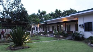 Una casa moderna con un césped cuidado, una pérgola y diversas plantas.