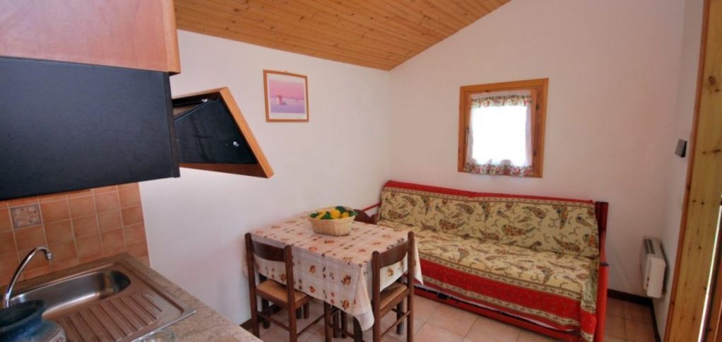 A compact kitchen with a sink, a dining table with chairs, and a sofa.