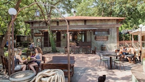 An outdoor seating area with tables and chairs, a wooden barrel, and a cat. - Bungalow Village Le Caravelle - by Mamberto S.r.l. (Ceriale)