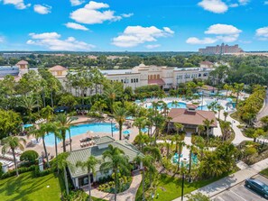 A resort with multiple swimming pools, palm trees, and a large building in the background. - Gentle Breeze at Vista Cay Resort (Orlando)