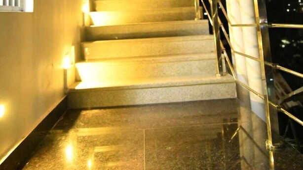 A well-lit staircase with a metal railing, leading to an upper floor. - Hotel Waanderers Howff (Port Blair)